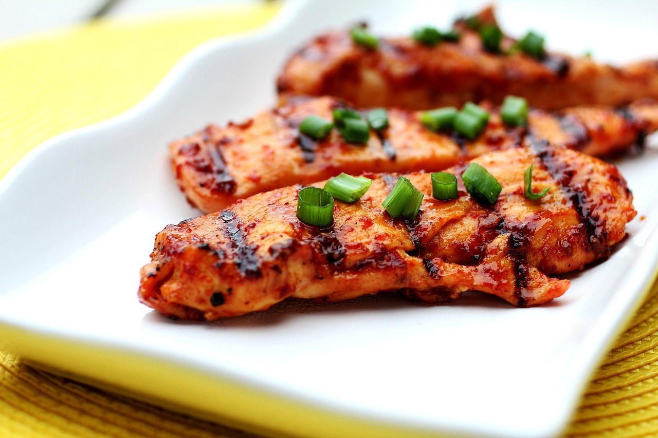 3 grilled chicken breasts on a plate with seasoning on top