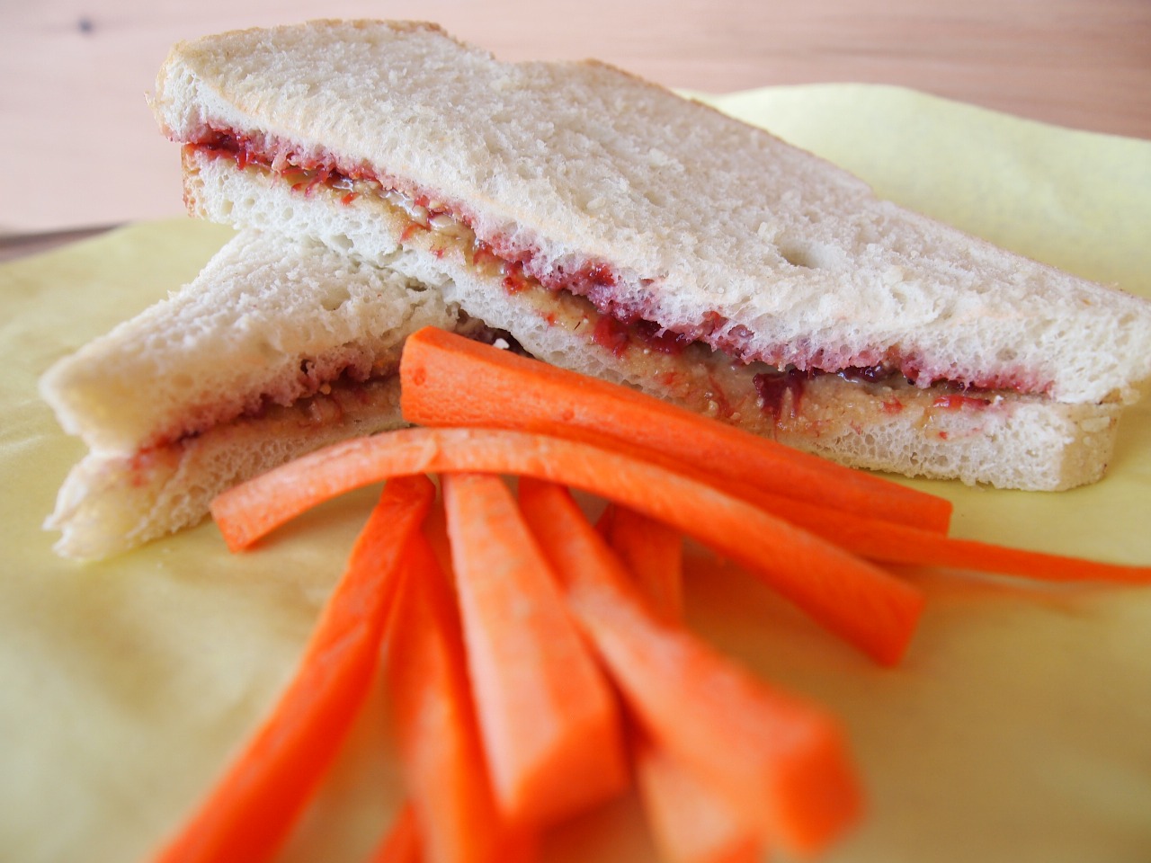peanut butter jelly sandwhich on a table with carrots