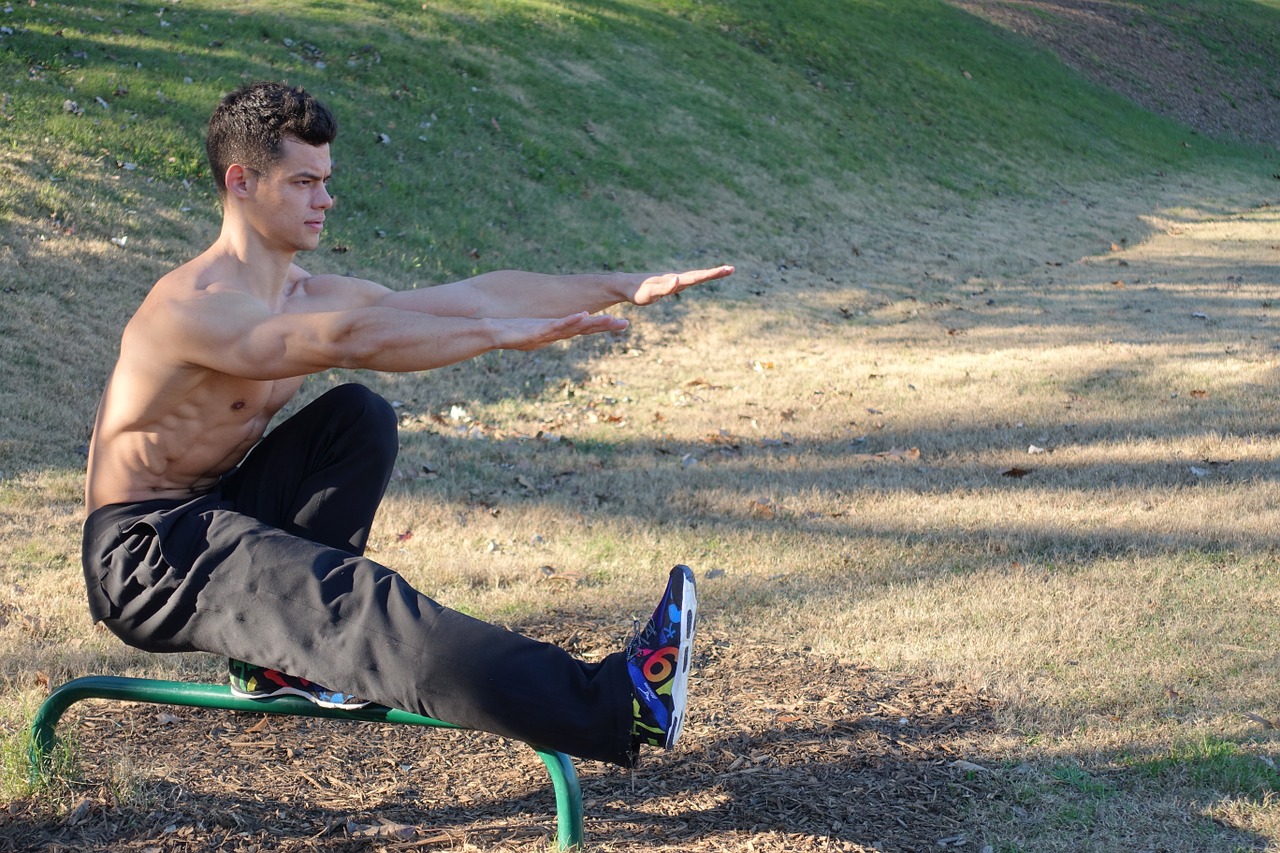 A man in a park performing the pistol sit