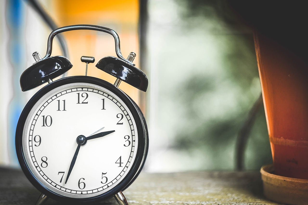 A traditional looking alarm clock sitting on a nightstand