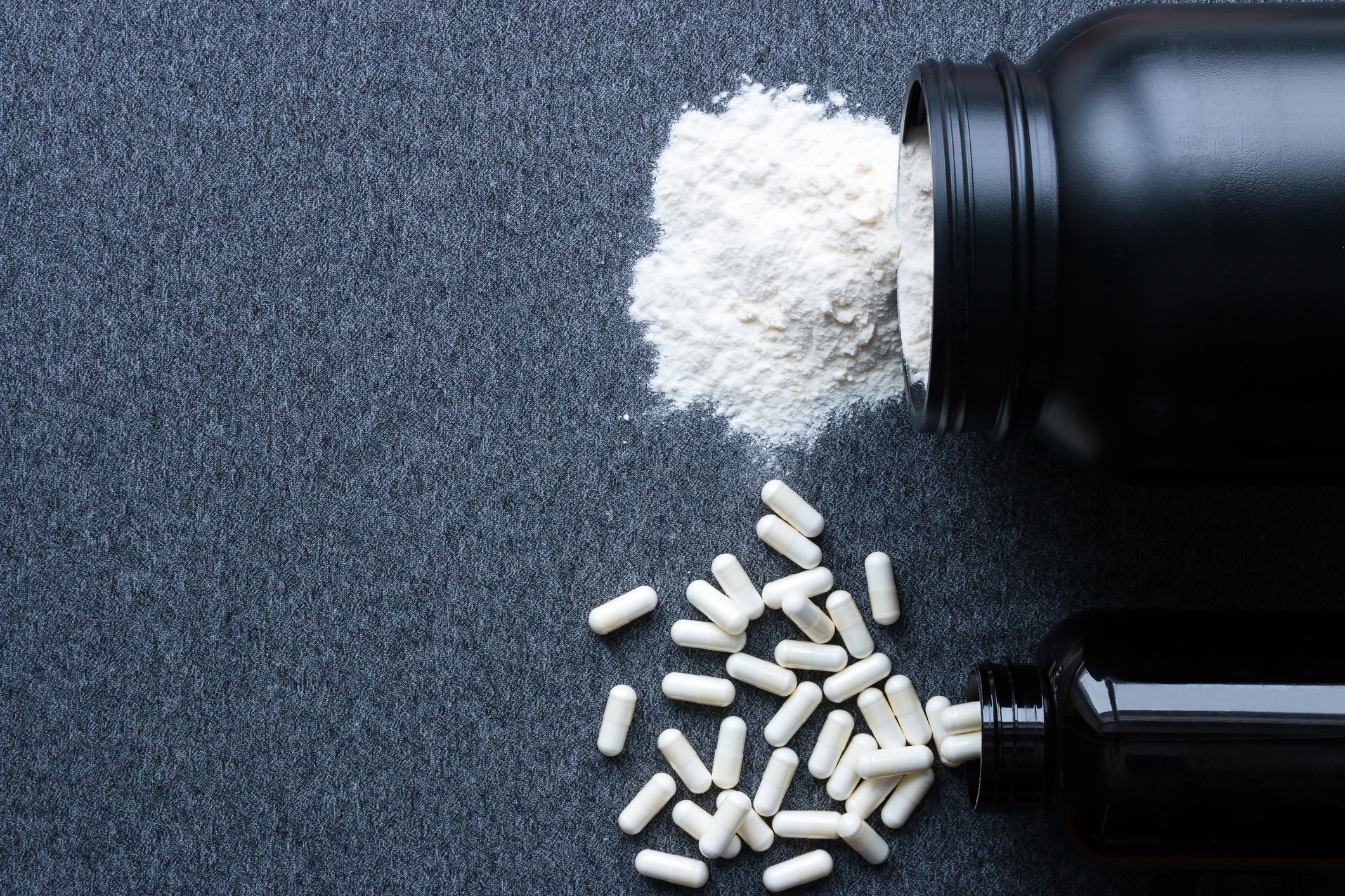 jars of creatine in powder and pill form spilling on a table during the creatine loading phase