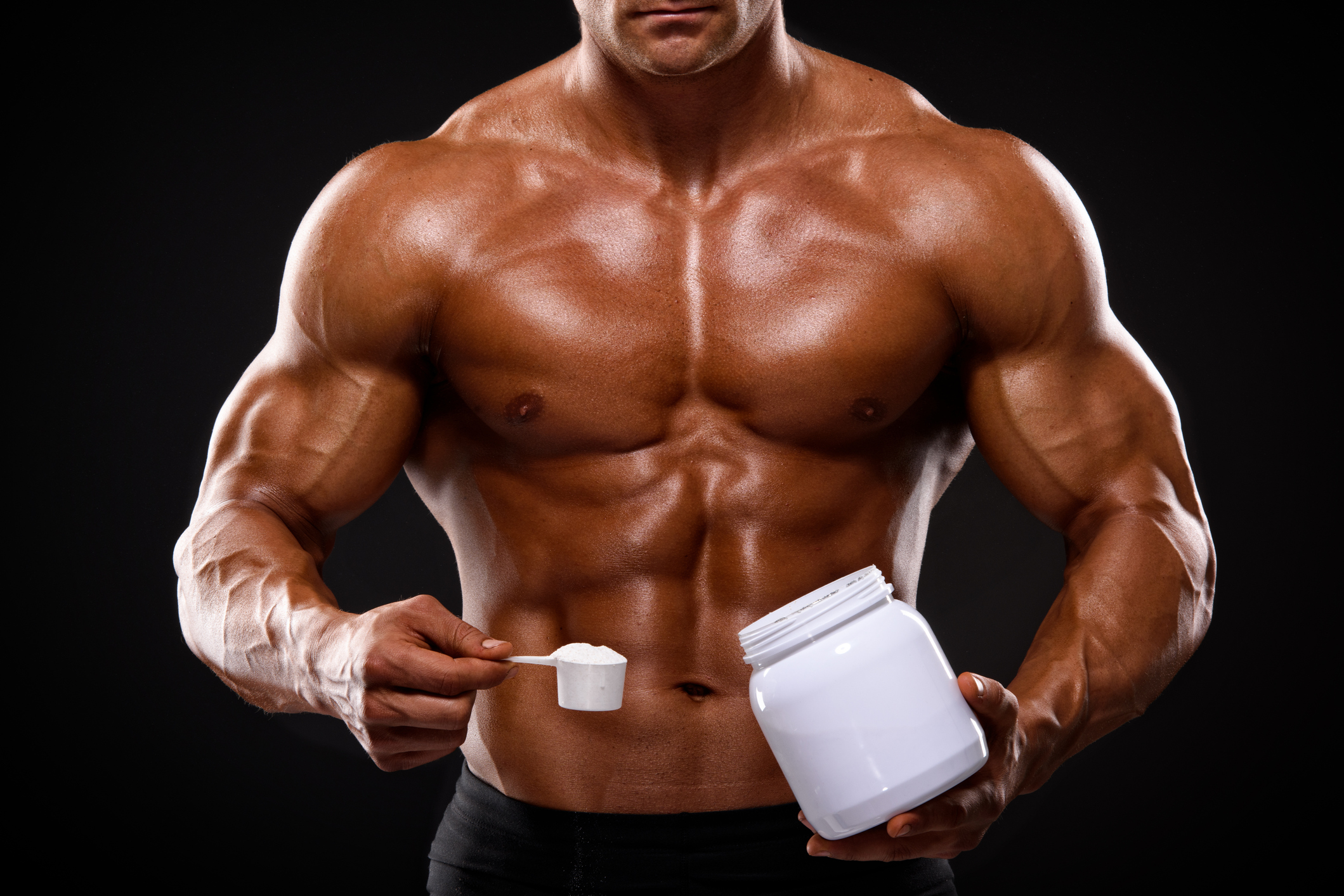 muscular shirtless man torso holding tub of creatine explaining when to take creatine